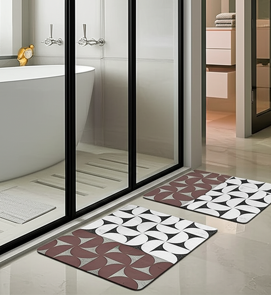 Two patterned bath mats on a bathroom floor with a glass shower enclosure in the background.